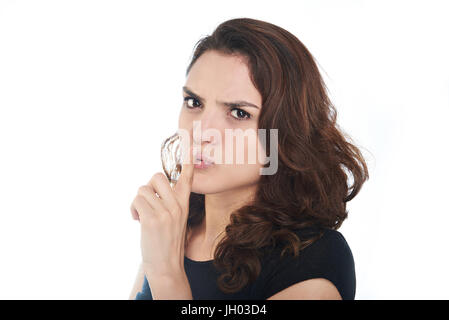 Frau zeigen Stille Zeichen isoliert auf weißem Hintergrund. Junge Frau halten Finger neben Lippen Stockfoto