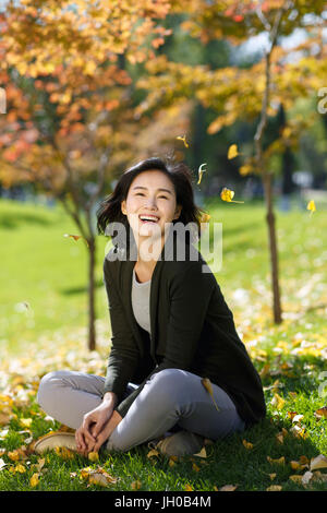 Junge Frau sitzt auf Laub Gras Stockfoto