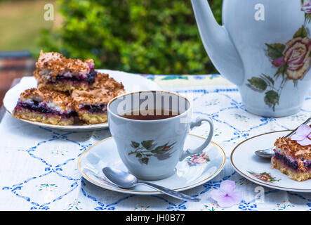 Tee und schwarzen Johannisbeeren Kuchen, begib dich auf einen Tisch im Garten Stockfoto