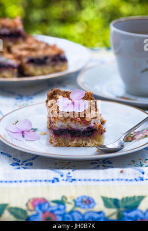 Johannisbeer Kokos Slice mit Tee auf einem Tisch im Garten Stockfoto