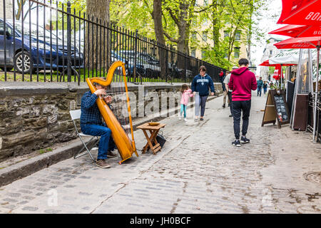 Quebec Stadt, Kanada - 29. Mai 2017: Alte Stadt Straße mit Kopfsteinpflaster mit Person spielt die Harfe sitzen im Freien von Restaurants im Sommer mit Bürgersteig Stockfoto