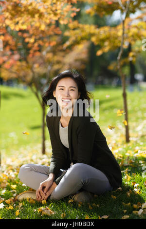 Junge Frau sitzt auf Laub Gras Stockfoto