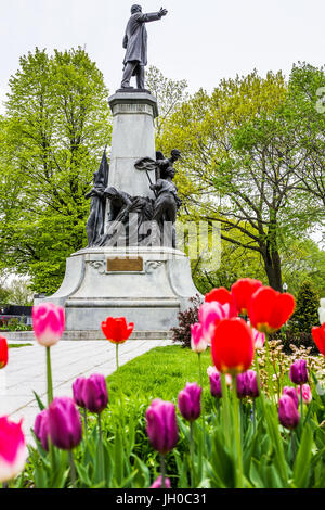 Quebec Stadt, Kanada - 29. Mai 2017: Makro Nahaufnahme von orange und gelb doppelt gestreiften roten Tulpen im Sommer von Parlament Park mit statue Stockfoto