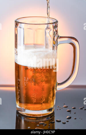 Strom von Bier in das Glas ergießt Stockfoto