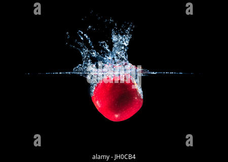 Roter Apfel und Wasser Spritzen auf schwarzem Hintergrund isoliert Stockfoto