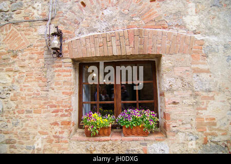 Alte Steinmauer mit Fenster und 2 Töpfe mit Stiefmütterchen Stockfoto