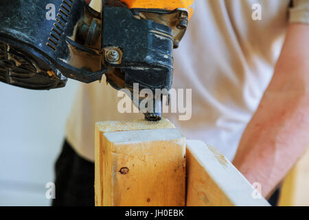 Bau der Waffe schießen die Nägel in die Holzwand Stockfoto