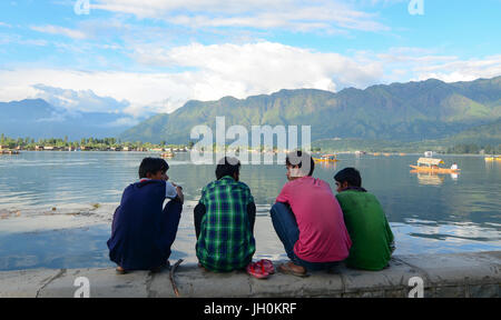 Srinagar, Indien - 23. Juli 2015. Indische Männer sitzen am Ufer des Dal-See in Srinagar, Indien. Srinagar ist die größte Stadt und die Sommer-Hauptstadt Stockfoto