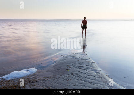 Ein Mann steht, gegen einen schönen, seidigen ruhiges Meer. Stockfoto