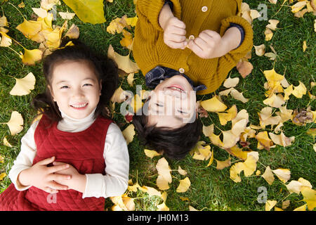 Zwei Kinder auf Laub Gras liegend Stockfoto