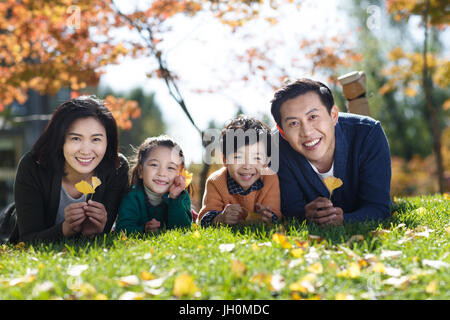 Familie mit zwei Kindern auf Laub Gras liegend Stockfoto