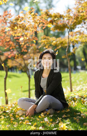 Junge Frau sitzt auf Laub Gras Stockfoto