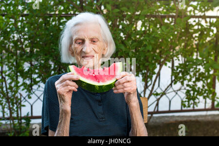 Ältere Frau Essen Wassermelone Frucht im Hinterhof Stockfoto