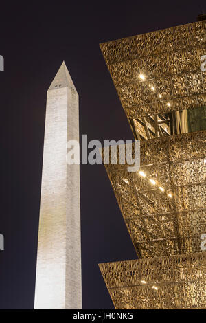 Die eckige Metall Architektur des National Museum of African American History und Kultur kontrastiert mit dem Washington Monument in der Nacht. Stockfoto