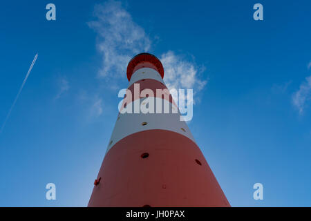 Ein Kondensstreifen eines Flugzeugs neben einem Leuchtturm in der deutschen Nordsee-Region Stockfoto