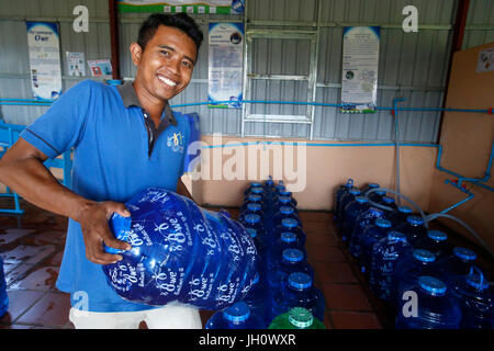 1001 Brunnen Wasser Unternehmen. Mitarbeiter tragen eine Korbflasche. Kambodscha. Stockfoto