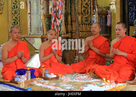 Sitzende buddhistische Mönche singen und gebeten an einer buddhistischen Zeremonie zu lesen. Wat Simuong. Wat Si Muang. Vientiane. Laos. Stockfoto