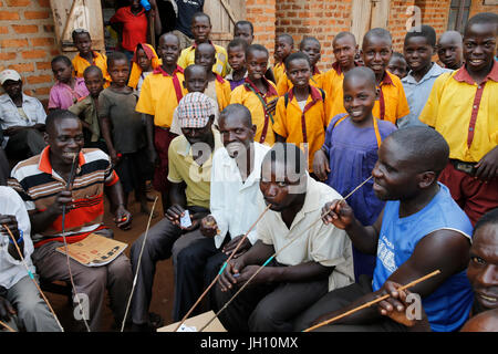 Ugandische Dorfbewohner selbst gebrautes Bier trinken und Schulkinder. Uganda. Stockfoto