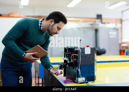 Junger Ingenieur testen seinen Roboter in Werkstatt Stockfoto