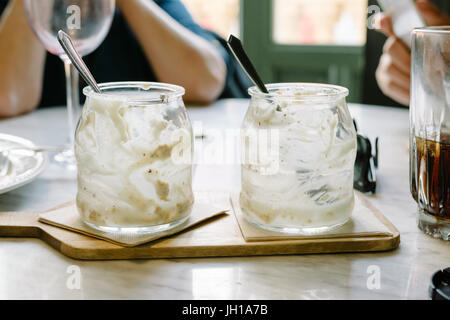 Glas Dessert gegessen, Löffel, mit Resten von Tiramisu, am Tisch im Restaurant auf Holzbrett. Aus Fokus diners Stockfoto