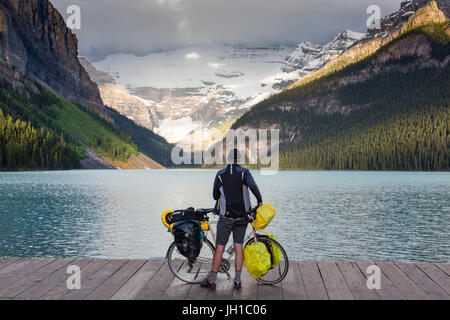 Ein männlicher Radfahrer genießt die Aussicht über Lake Louise am frühen Morgen sein Fahrrad mit gedrückter. Lake Louise, Banff Nationalpark, Alberta, Kanada Stockfoto