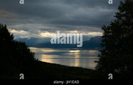 Verstreuten Lichtfilter durch kleine Löcher in den schweren Wolken Strahlen des Lichtes an der Kachemak Bay bieten. Stockfoto