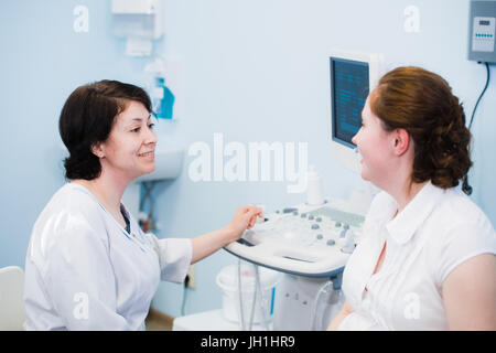 Zufrieden schwangere Frau, die ärztliche Visite mit Ultraschalldiagnostik Stockfoto