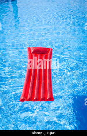 Rote aufblasbare Lilo liege schwebend in einem Schwimmbad Stockfoto