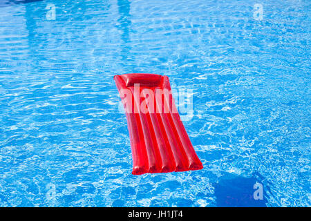 Rote aufblasbare Lilo liege schwebend in einem Schwimmbad Stockfoto