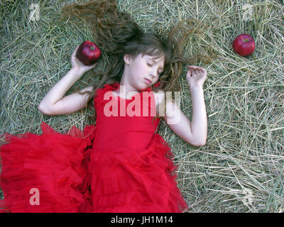 kleines Mädchen im roten Kleid schlafen auf dem Heuhaufen im Sommertag Stockfoto