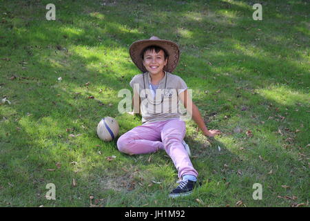 10-Jahr-alte Junge sitzt in einem Garten. Frankreich. Stockfoto