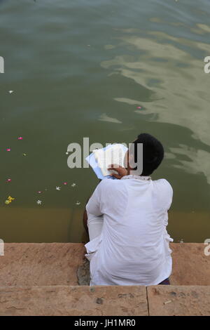 Hindu ein spirituelles Buch auf der Treppe zu Goverdan Radha Kund. Indien. Stockfoto