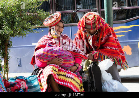 Happy, lächelnde einheimische peruanischen Ehepaar aus der Region Cusco. Quechua-Frau hält ihr Baby in bunte handgemachte traditionelle Outfit gekleidet. Oktober Stockfoto