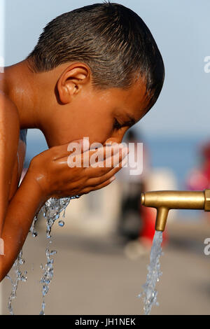 Junge Trinkwasser aus einem Brunnen. Italien. Stockfoto