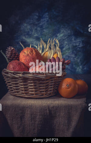 Stillleben-Stil Rot Baby Jackfrucht und trockenen Mais in alten Korb Stockfoto
