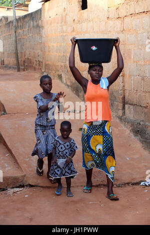 Afrikanisches Dorfleben.   Wasser mühsam.  Afrikanische Mädchen tragen eine Schüssel mit Wasser auf Kopf.  Togoville. Togo. Stockfoto