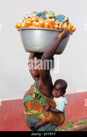 Frau, die die Platte mit Mais auf Kopf. Togo. Stockfoto
