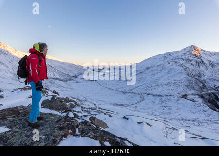 Wanderer auf dem felsigen Kamm bewundert die schneebedeckten Gipfel der Fjordbotn, Lysnes, Senja, Troms, Norwegen, Skandinavien, Europa Stockfoto