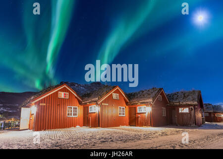 Die Nordlichter und Mond Leuchten typischen hölzernen Hütten genannt Rorbu, Manndalen, Kafjord, Lyngen Alpen, Troms, Norwegen Stockfoto