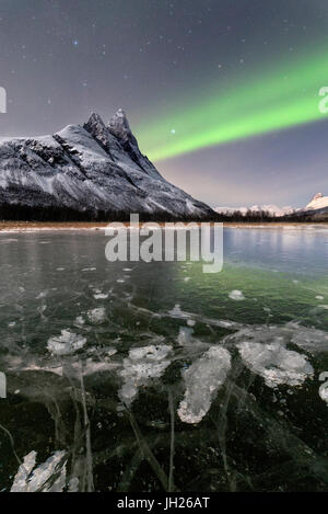 Eis-Bläschen gefrorene Meer und schneebedeckten Gipfel des Otertinden unter dem Nordlicht, Oteren, Lyngen Alpen, Troms, Norwegen Stockfoto