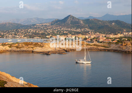 Ein Segelboot im kristallklaren Meer rund um das Dorf von Ile Rousse bei Sonnenuntergang, Balagne Region, Korsika, Frankreich, Mittelmeer, Europa Stockfoto