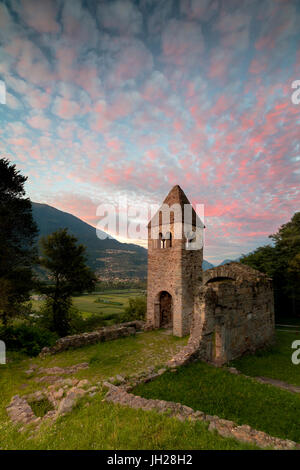 Rosa Wolken bei Sonnenuntergang auf der alten Abtei San Pietro in Bregalone, Piagno, Sondrio Provinz, unteren Veltlin, Lombardei, Italien Stockfoto