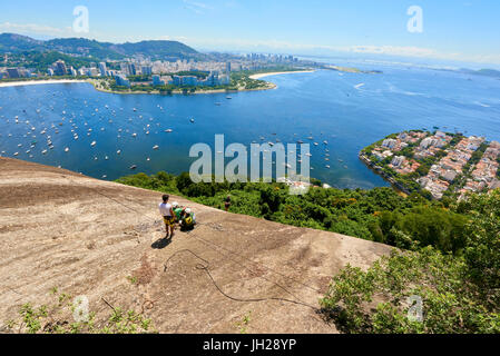 Abseilenden in Morro da Urca in Rio De Janeiro mit Panoramablick in den Hintergrund, Rio De Janeiro, Brasilien, Südamerika Stockfoto