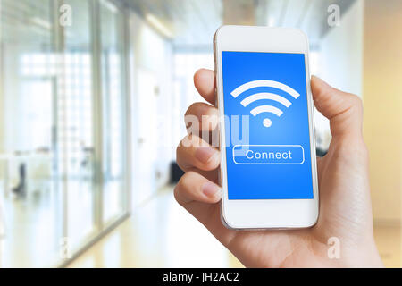 Hand, die eine Smartphone mit einer Taste zum Verbinden mit eines kostenfreier WLAN-Hotspots mit WLAN-Symbol auf dem Bildschirm Stockfoto