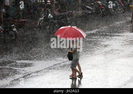 Schweren Monsunregen. Paar mit Regenschirm auf Saigon Street. Vietnam. Stockfoto