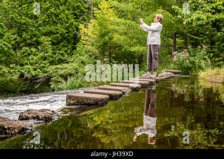 Frau ist das Fotografieren eines Baches in Michigans obere Halbinsel Stockfoto