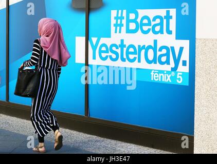 Eine junge muslimische Frau geht durch ein Einkaufszentrum und eine riesige Werbung Lesung "#Beat gestern" im Zentrum von Berlin am 2. Juni 2017.  Foto: Wolfram Steinberg/Dpa | weltweite Nutzung Stockfoto