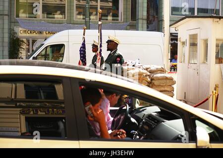 Zwei schwarze Mann verkleidet als uns Soldaten Posen für Geld für Touristen, die ihre Foto am Checkpoint Charlie in Berlin-Mitte am 19. Juni 2017 zu machen. Im Vordergrund sitzt ein Tourist in ein Taxi und spricht in sein Handy. Dieses Bild ist Teil einer Serie o | weltweite Nutzung Stockfoto