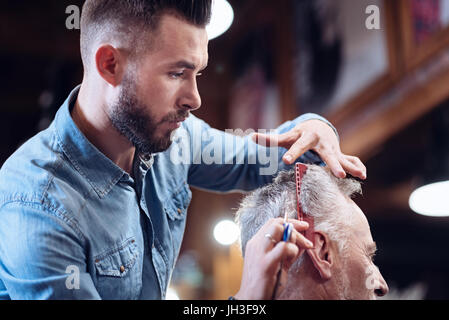 Angenehme nette Friseur seinen Kunden Haar kämmen Stockfoto