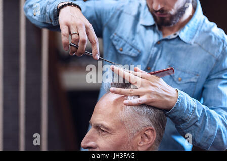 Schön schön Friseur hält seine Kunden Haar Stockfoto